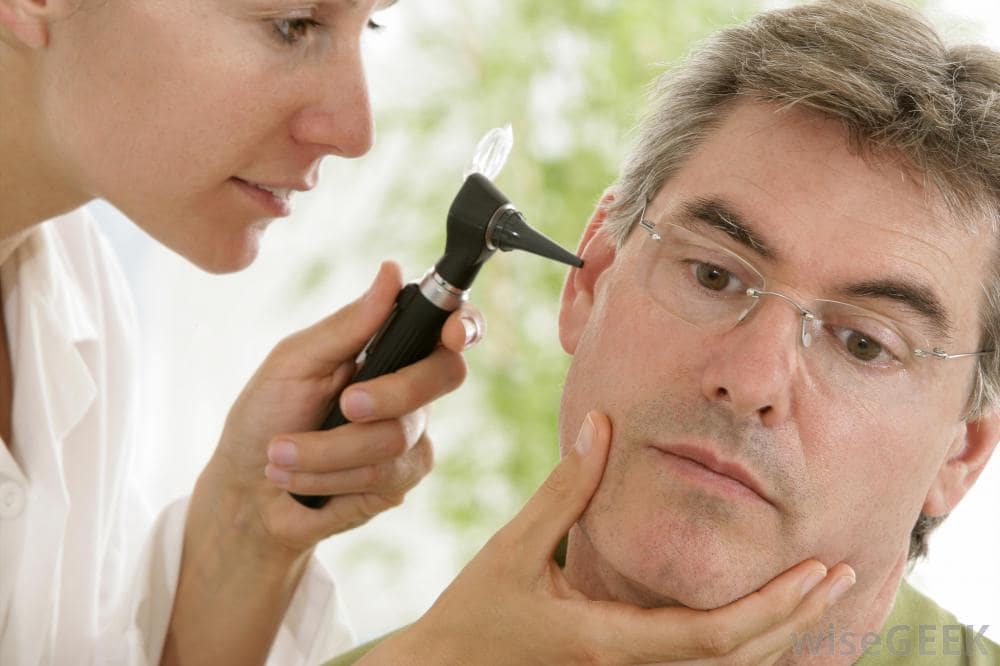 physician examines ear of male patient min